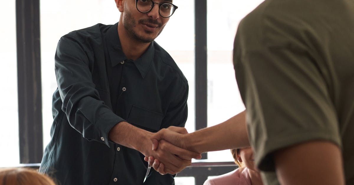 Diverse colleagues engaging in a business meeting indoors, sealing a deal with a handshake.